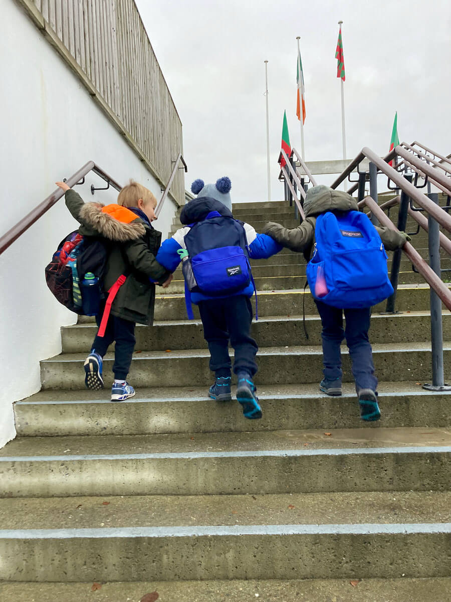 Photo of 3 children going up the steps of the school